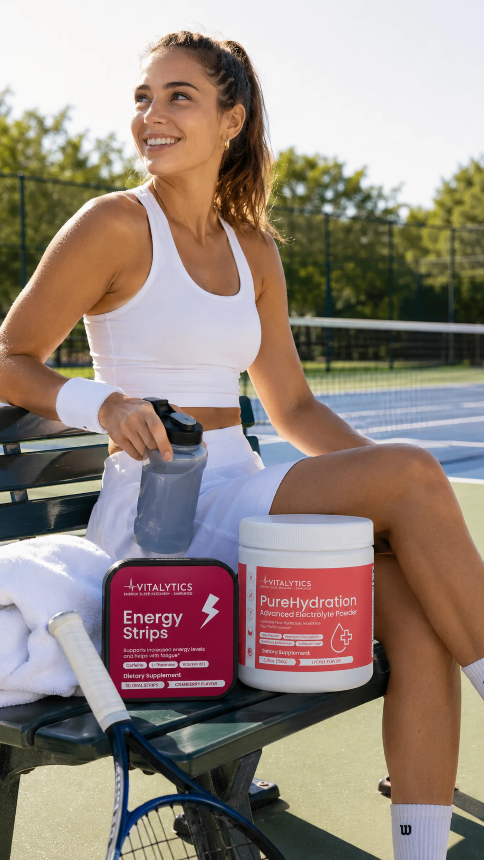 Tennis player resting on a bench with Energy Strips and PureHydration beside her on the court.